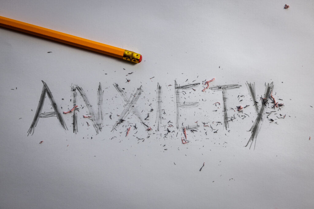 Anxiety anxiously etched onto paper and attempted to be erased with a pencil and eraser shavings layered overtop. Anxiety disorder awareness and treatment concept